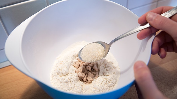 In einer Schüssel wird Mehl mit Hefe und Zucker vermischt. | Bild: picture-alliance/dpa
