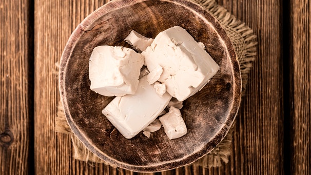 Frische Hefewürfel von oben in einer Schale, die auf einem Holztisch steht.  | Bild: mauritius images / Handmade Pictures / Alamy