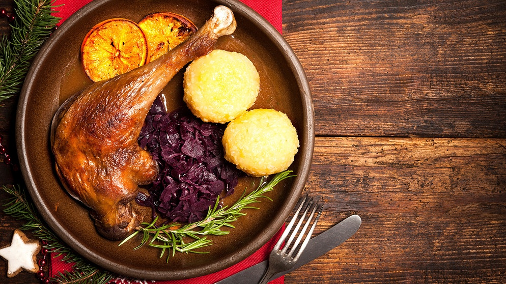 Ein Teller mit einer Gänsekeule, zwei Kartoffelknödeln und Blaukraut | Bild: mauritius images / Alexander Raths