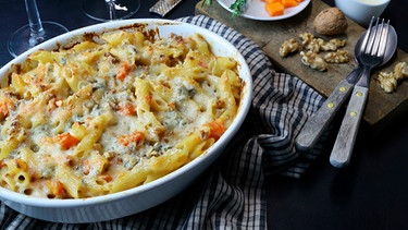 eine weiße Schale Nudelauflauf mit Kürbis, Gorgonzola und Walnüssen, der mit Käse überbacken ist, auf einem Küchentuch; Ansicht von oben; | Bild: mauritius images / Grazziela Bursuc / Alamy / Alamy Stock Photos