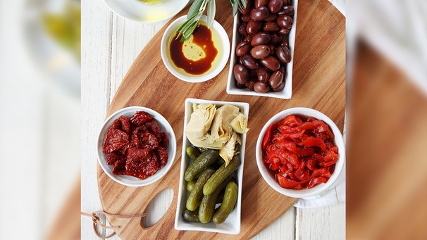 Verschiedene Antipasti (getrocknete Tomaten und Paprika, Kalamata-Oliven, Essiggurken, Artischocken, Olivenöl mit Balsamico) | Bild: mauritius images / foodcollection