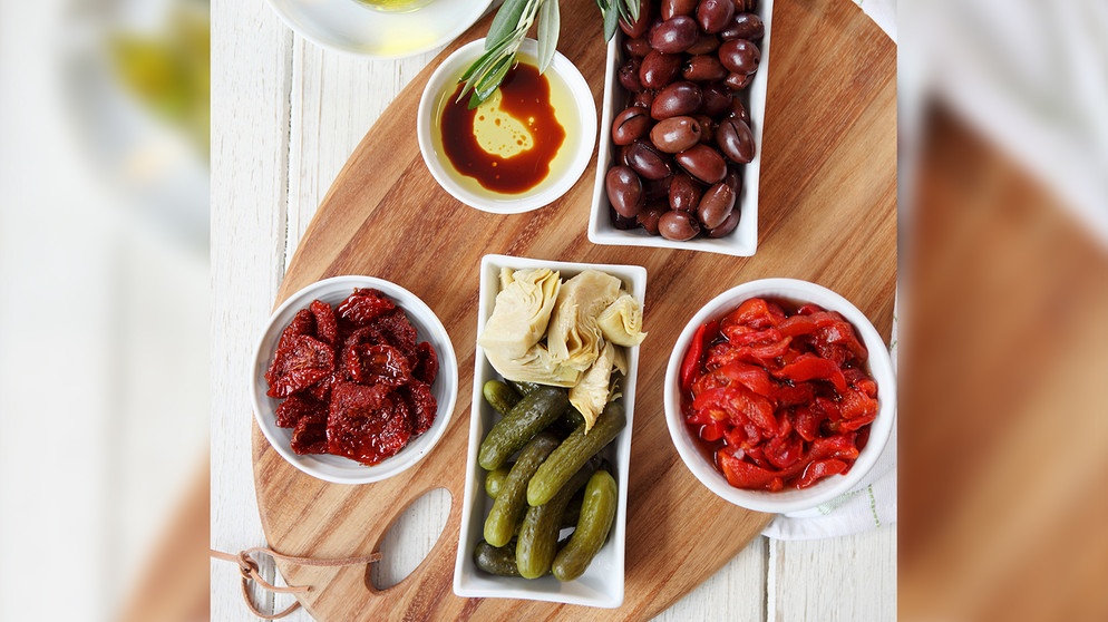 Verschiedene Antipasti (getrocknete Tomaten und Paprika, Kalamata-Oliven, Essiggurken, Artischocken, Olivenöl mit Balsamico) | Bild: mauritius images / foodcollection