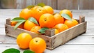 Orangen in einer Vintage-Holzkiste auf einem Holztisch | Bild: mauritius images / Image Source / Diana Miller