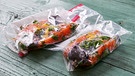 Zwei Gefrierbeutel gefüllt mit Lachs mit Kräutern vakuumiert auf einem Tisch | Bild: mauritius images / foodcollection / Hans Gerlach