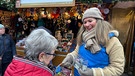 Der Sternstundenstand am Nürnberger Christkindlesmarkt: "Wir in Bayern"-Mitarbeiterin Faika von Sandizell nimmt die Spende einer Besucherin entgegen | Bild: BR