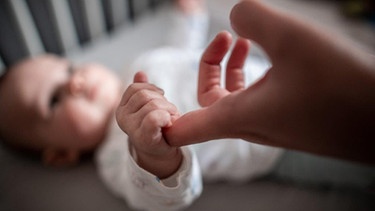 Baby umklammert Finger der Mutter | Bild: picture-alliance/dpa