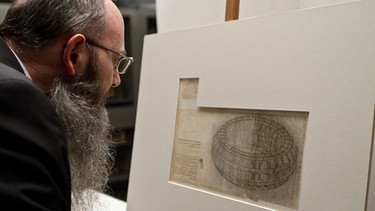 Don Francesco Braschi ist in der Biblioteca Ambrosiana in Mailand verantwortlich für die Aufbewahrung des Codex Atlanticus, der wichtigsten Sammlung von Zeichnungen, Skizzen und Notizen Leonardos. | Bild: BBC/BR/IWC Media/Allessandra Di Gregorio