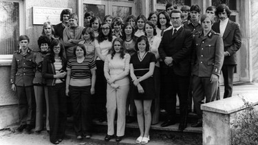 Klassentreffen in Golzow, 26. April 1975. Viele der Jungen sind jetzt Soldaten. Nie wieder kamen so viele auf ein gemeinsames Bild. 1. Reihe, von links: N.N., die erste Lehrerin Marlies Teike, etc.; 2. Reihe: N.N., Eckhard, Dieter, (hinter ihm links: Eckhard, hinter ihm rechts: Winfried), N.N., N.N., Marieluise (hinter ihr links: Brigitte), Elke, N.N. (dahinter verdeckt: Gudrun) und Bernd (hinter ihm rechts: Willy) . | Bild: Honorarfrei lediglich für Ankündigungen und Veröffentlichungen im Zusammenhang mit obiger BR-Sendung bei Nennung: Bild: BR/Progress Film-Verleih/DEFA. Die Nutzung im Social Media-Bereich, sowie inhaltlich andere Verwendungen nur nach vorheriger schriftlicher Vereinbarung mit dem BR-Bildarchiv, Tel. 089 / 5900 10580, Fax 089 / 5900 10585, Mail Pressestelle.foto@br.de