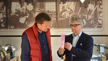 Jens Hübschen mit Constantin Wild, Farbedelsteinhändler in Idar-Oberstein und seinem Edelsteinschleifer Gernot Mayer in der Schleifwerkstatt. | Bild: BR/SWR/Constantin Wild