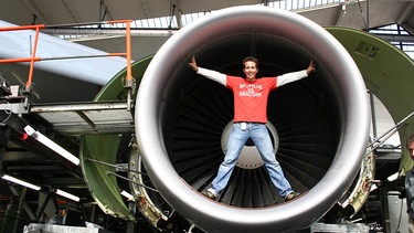 Willi Weitzel zeigt, wie groß eine Flugzeugturbine sein kann. Ihn interessiert heute, warum Flugzeuge eigentlich fliegen. | Bild: BR/megaherz gmbh