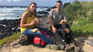 Tamina Kallert (l) und Wanderführer Tiago Botelho machen ein Picknick an der Küste von Mosteiros auf der Hauptinsel Sao Miguel. | Bild: WDR/Richard Hofer