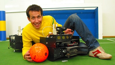 Willi Weitzel mit einem Fussballroboter. Heute erfährt er, dass ohne einen Computer und einem Programm kein Roboter funktioniert. | Bild: BR/megaherz gmbh/