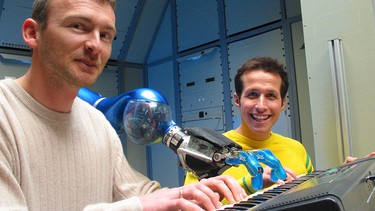 Willi Weitzel und Prof. Max Fischer mit einem Industrieroboter. Diese Roboterhand soll eines Tages Astronauten im Weltall helfen. | Bild: BR/megaherz gmbh/