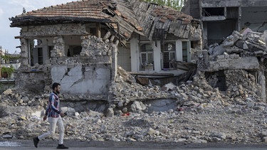 23.04.2023, Türkei, Kahramanmaras: Ein Mann geht in der Altstadt von Kahramanmaras an den Trümmern eingestürzter Wohnhäuser vorbei. | Bild: dpa-Bildfunk/Boris Roessler