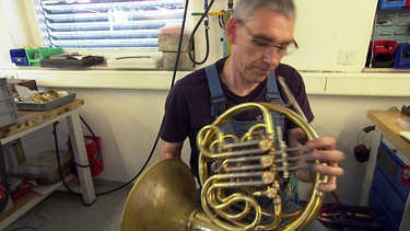 Blasinstrumentenbauer Eckard Graf prüft das von ihm gebaute Horn. | Bild: SWR