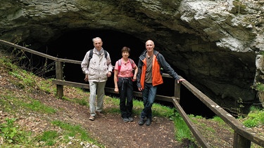 Die Wandergruppe (von links) mit Hans-Jürgen Grönke vom Nordhäuser Geschichtsverein sowie Elke Blanke und Tobias Strietzel vom BUND. Die drei stehen vor der Kelle, einer Grotte im Gipskarst. Einst war die Kelle eine Höhle, doch die Decke stürzte vor Jahrhunderten ein. | Bild: MDR/Mia Media