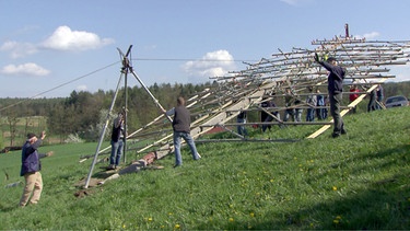 Im steirischen Stübing halten die Menschen viele alte Traditionen lebendig. Gerade das Osterfest ist hier voll von Bräuchen, die im Stübinger Freilichtmuseum dokumentiert sind. Es beginnt am sogenannten "schmerzhaften Freitag", an dem vor Sonnenaufgang der Palmbuschen gebunden wird. Am Karfreitag ließen die Menschen das sonst stets sorgsam bewachte Herdfeuer bewusst ausgehen. Am Samstag holten die Kinder dann das Weihfeuer von der Kirche, um den Herd neu zu entzünden. Mit einem Weihtuch bedeckten die Leute Selchfleisch und Kräuter. Dieses Weihtuch durfte nicht gewaschen werden und hing im Sommer am Zaun zum Schutz gegen Gewitter. Im Bild: Aufstellen eines Osterkreuzes. | Bild: ORF