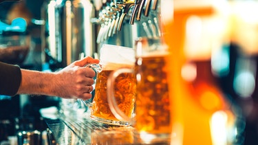 Ein Mann zapft ein Bier aus einer Zapfanlage. | Bild: stock.adobe.com/master1305