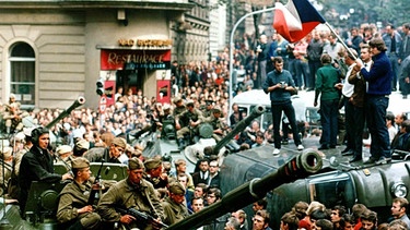 August 1968, Tschechoslowakei, Prag: Protestierer umringen in der Innenstadt sowjetische Panzer und stehen mit einer Fahne der Tschechoslowakei auf einem umgekippten Militärfahrzeug. | Bild: picture alliance/dpa | Libor Hajsky