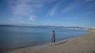 Eine Frau geht am letzten Tag des Jahres am Strand von Arenal auf Mallorca am Meer entlang.  | Bild: dpa-Bildfunk/Clara Margais