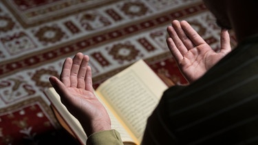 Islam und Antisemitismus: Wurzeln im Koran? / Ein islamischer Mann betet und liest aus dem Koran. | Bild: stock.adobe.com/Jale Ibrak