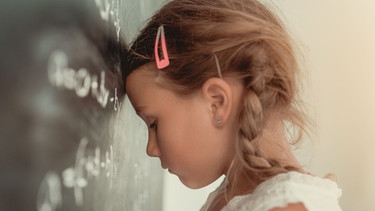 Ein Mädchen steht überfordert vor einer Tafel. | Bild: stock.adobe.com/detailblick-foto