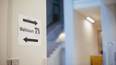 Ein "Wahlraum" Schild in einem Wahllokal. | Bild: BR/Julia Müller