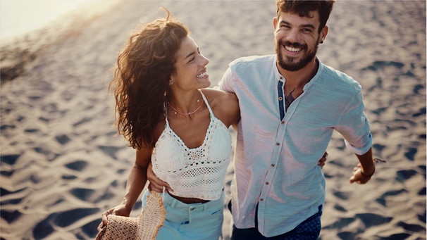 Ein glückliches Paar geht am Strand entlang. Endlich Ferien und ihr sehnt euch nach Erholung? Doch wie entspannt ihr im Urlaub am besten? Wir geben Tipps, wie ihr garantiert neue Kraft tanken könnt. | Bild: Wochit/ Getty Images