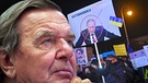 FOTOMONTAGE: Freunde und Partei wenden sich von Gerhard Schroeder ab, der Altbundeskanzler und Gaslobbyist will nicht mit Putin brechen. Trotz des Einmarsches in die Ukraine haelt Altkanzler Gerhard Schroeder an seiner Freundschaft zu Wladimir Putin und an seinen russischen Geschaeftsbeziehungen fest. Das Echo ist verheerend. Grossdemonstration gegen Wladimir Putin und die Invasion Russlands in die Ukraine 02.03.20222 auf dem Koenigsplatz in Muenchen. 40000 Menschen demonstrieren fuer Frieden in der Ukraine | Bild: picture alliance / SvenSimon | Frank Hoermann/SVEN SIMON