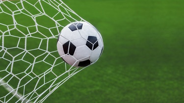 Eine Nahaufnahme von einem Fußball, der ins Tor geschossen wird. | Bild: stock.adobe.com/anekoho