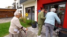 Junge Frau ist einer Seniorin behilflich | Bild: Bayerischer Rundfunk 2024