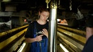 Junge Frau mit Werkzeug steht in einer Autowerkstatt | Bild: Bayerischer Rundfunk 2023