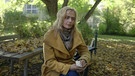 Eine Frau sitzt auf einer Bank in einem Park | Bild: Bayerischer Rundfunk