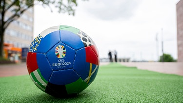 Ein Fußball liegt auf dem ersten Teppichabschnitt für die UEFA EURO 2024. Während der Europameisterschaft verläuft ein grüner Teppich durch die Innenstadt von Dortmund (Nordrhein-Westfalen, Deutschland) | Bild: dpa-Bildfunk/David Inderlied