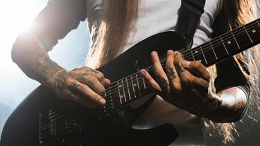 Ein Mann mit sehr langen Haaren spielt auf einer E-Gitarre. | Bild: colourbox.com