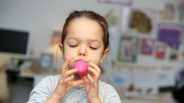 Mädchen bläst Luftballon auf. | Bild: picture-alliance/dpa