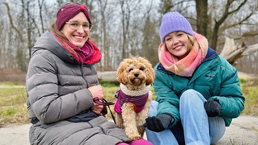 Wecher Hund passt zu mir? | Hundetrainerin Leandra (links) zeigt Nina einen typischen Begleithund: Der kleine Cooper ist ein Cavapoo, eine Mischung aus Cavalier King Charles Spaniel und Pudel (Dr. Leandra Sabass). | Bild: BR | Text und Bild Medienproduktion GmbH & Co. KG | Katharina Brackmann