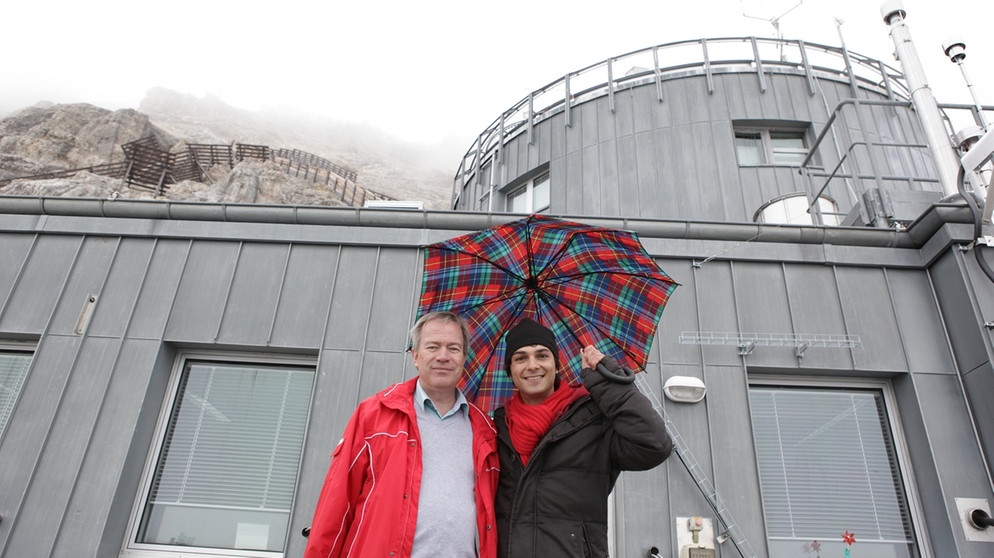 Der Wetter-Check / Can (rechts) mit Prof. Stefan Emeis vor der Wetterstation auf der Zugspitze | Bild: BR/megaherz gmbh/Hans-Florian Hopfner