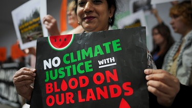 Aktivisten nehmen im November 2024 mit Schildern mit der Aufschrift "No Climate Justice with Blood on our Lands" an einer Demonstration für Klimagerechtigkeit auf dem Cop29-Klimagipfel teil. | Bild: dpa-Bildfunk/Peter Dejong