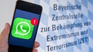 Ein Mobiltelefon mit dem Logo des Messenger-Dienstes "WhatsApp" vor dem Schriftzug "Bayerische Zentralstelle zur Bekämpfung von Extremismus und Terrorismus". | Bild: pa/dpa/Peter Kneffel
