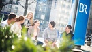 Jugendliche sitzen vor dem BR-Hochhaus. | Bild: BR/Simon Heimbuchner