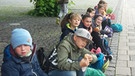Die Klasse 4c am Agilolfinger Platz sitzen auf dem Bürgersteig und warten darauf, dass der Ausflug beginnt.  | Bild: BR/ Friederike Breyer