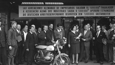 Der millionste Gastarbeiter erhält ein Moped als Geschenk bei seiner Ankunft in Deutschland. | Bild: picture-alliance/dpa