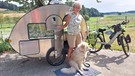 Susi Kronstein steht mit ihrem Hund Patchi vor ihrem Fahrrad-Wohnwagen. | Bild: BR/Susanne Ilse
