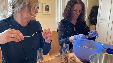 Dorfbewohnerinnen im mittelfränkischen Sammenheim verpacken gezuckerte Walnüsse aus dem Ort für den großen Nussmarkt. | Bild: BR / Ulrike Lefherz