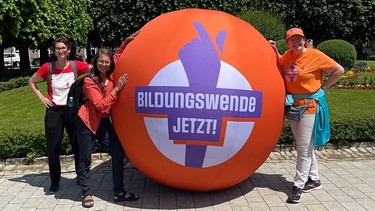 Drei Frauen stehen an einem orangenen Ball, auf dem "Bildungswende Jetzt!" steht. | Bild: Bündnis "Bildungswende Jetzt!"