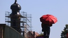 ARCHIV (19.07.2022): Ein Mann geht mit einem roten Sonnenschirm über die Alte Mainbrücke. Seit 2015 hält Kitzingen den bayerischen Temperaturrekord. | Bild: picture alliance/dpa | Karl-Josef Hildenbrand