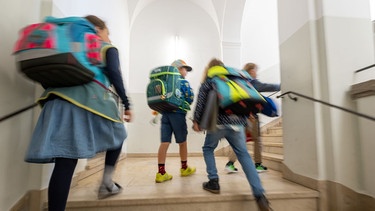 Symbolbild: Kinder mit Schulranzen laufen die Treppe einer Grundschule hoch. | Bild: picture alliance/dpa | Peter Kneffel