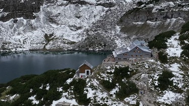 Die Coburger Hütte liegt inmitten halb verschneiter Felsen über dem Drachensee. | Bild: BR / Ulrike Nikola