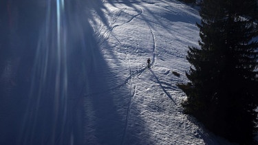 Ein Tourengeher geht im Sonnenschein neben der Skipiste am Söllereck durch den Schnee. | Bild: dpa-Bildfunk/Karl-Josef Hildenbrand